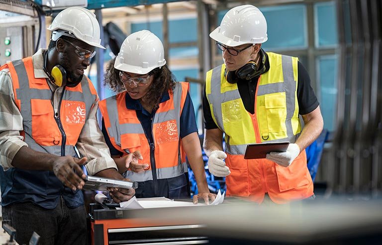 reduce manufacturing waste solution. group of manufacturing process engineers having a discussion about welding assembly process improvement to reduce parts defect during production in front of the production line.